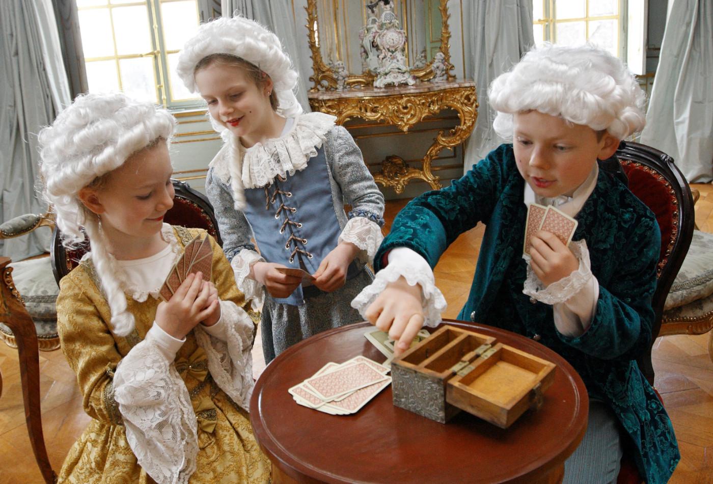 Kinder in herzoglichen Kostümen spielen Karten