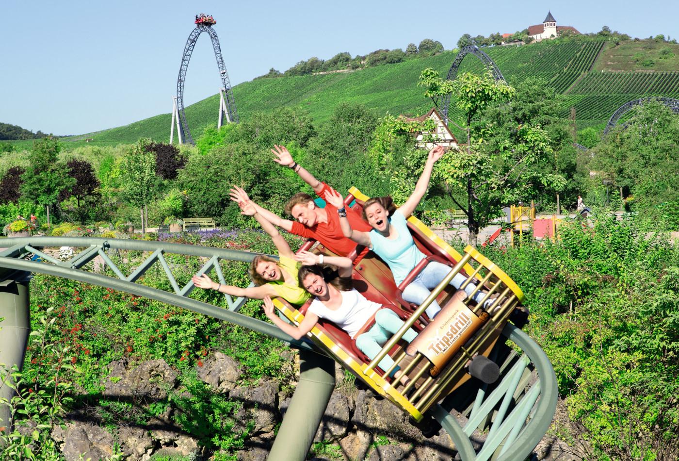 Drei Frauen und ein Mann fahren mit hochgestreckten Armen in der Gsengten Sau im Erlebnispark Tripsdrill