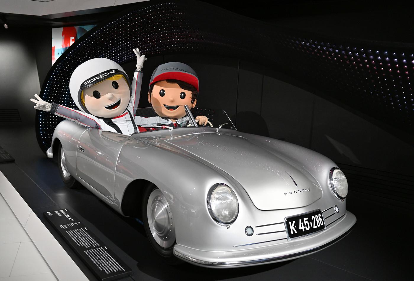 Tina Turbo und Tom Targa sitzen in einem silbernen Porsche Cabrio