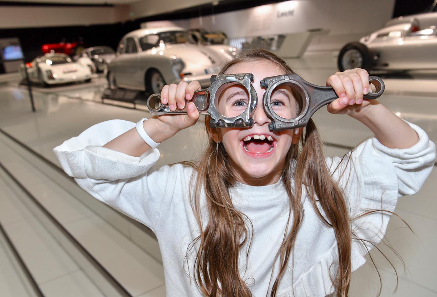 Mädchen hält sich zwei Autoteile vor die Augen, wie eine Brille