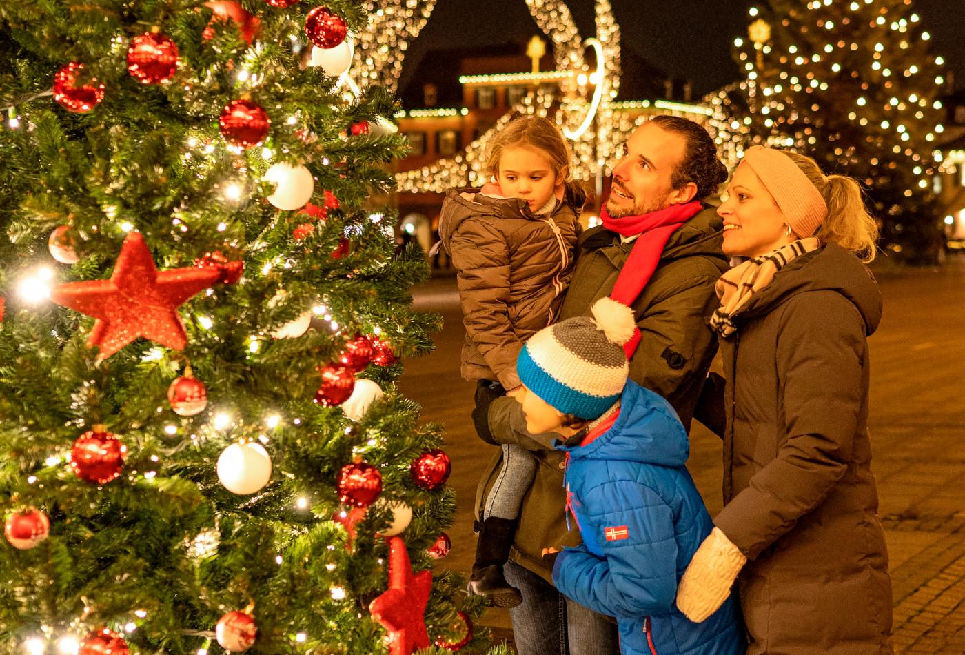 Familie steht vor einem festlich geschmückten Weihnachtsbaum auf dem Ludwigsburger Marktplatz