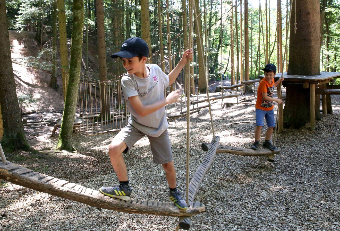 Zwei Jungen klettern auf einem Niederseil-Parcours im Wald