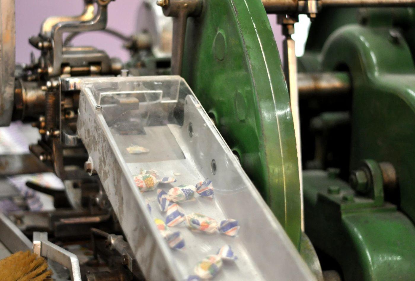 Mehrere verpackte Bonbons liegen auf einem Förderband einer alten Bonbon-Maschine