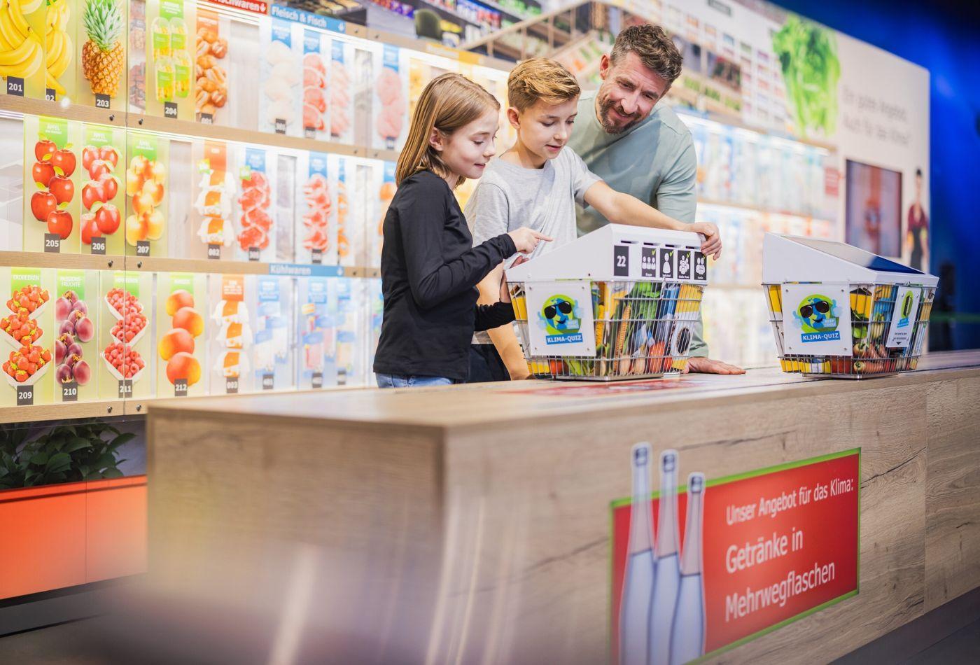 Zwei Kinder und ein Mann kaufen im "Klima-Supermarkt" ein