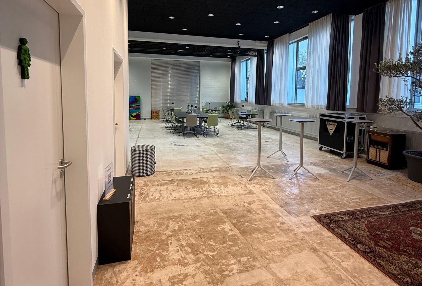 Blick auf einen Veranstaltungsbereich mit Stehtischen im Vordergrund