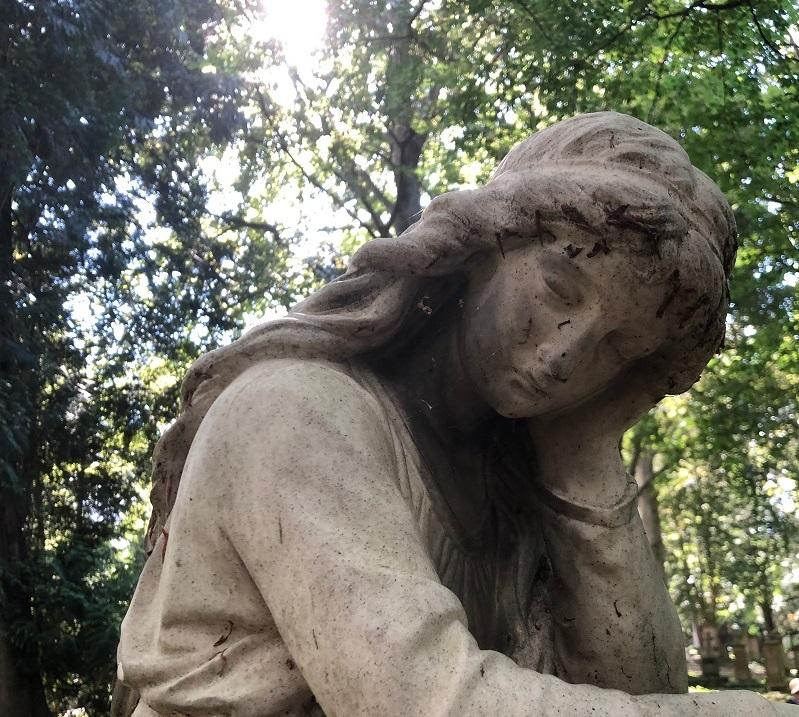 Eine steinerne Statue stützt den Kopf auf den Arm und lehnt sich an einen Sockel Eine steinerne Statue stützt den Kopf auf den Arm und lehnt sich an einen Sockel