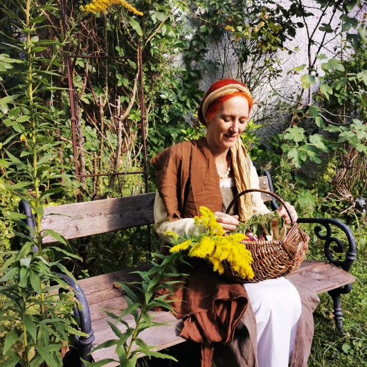 Zu sehen ist eine sitzende Dame mit Korb.