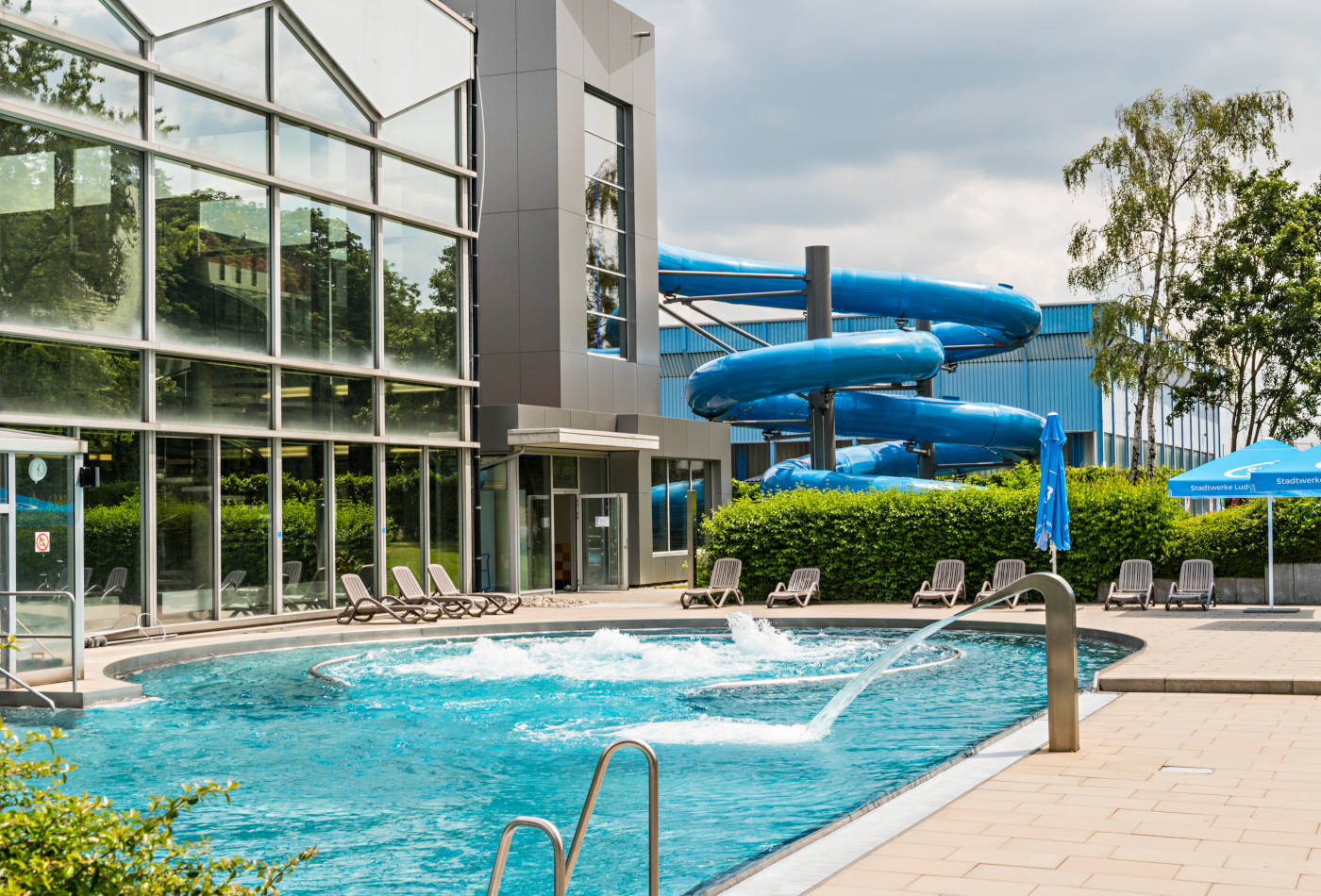 Außenbecken eines Schwimmbades mit blauer Ringelrutsche