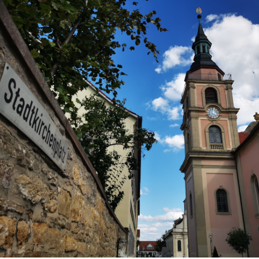 Zu sehen ist die Stadtkirche sowie das Straßenschild des Stadtkirchenplatzes.