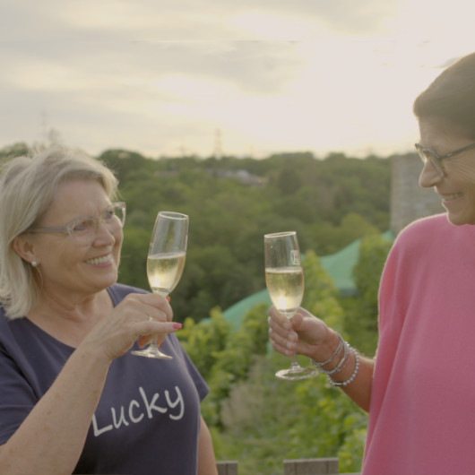 Zwei Damen, die Sektgläser halten und anstoßen.