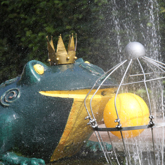 Figur des Froschkönigs mit Wasserspiel im Hintergrund