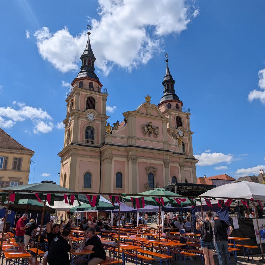 Blick auf die Stadtkirche mit Biertischen und Bänken und Sonnenschirmen im Vordergrund