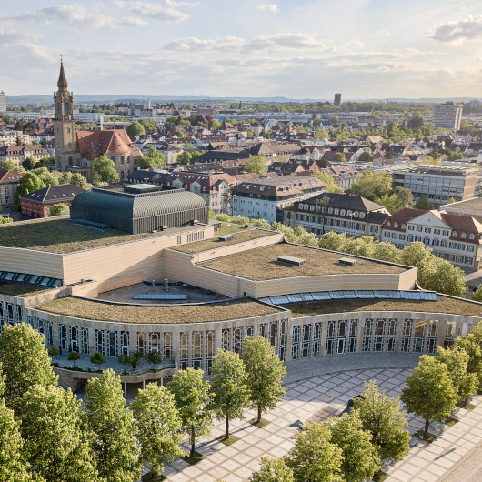 Luftaufnahme vom Forum am Schlosspark mit grünen Bäumen und blaubem Himmel.