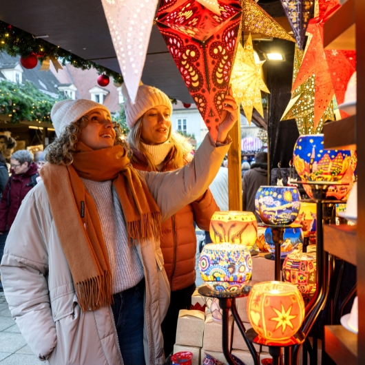 Zu sehen sind zwei Frauen an einem Weihnachtsmarktstand
