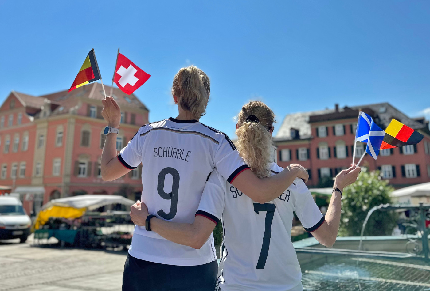 2 Frauen in Fußballtrikots stehen mit dem Rücken zur Kamera auf dem Marktplatz in Ludwigsburg