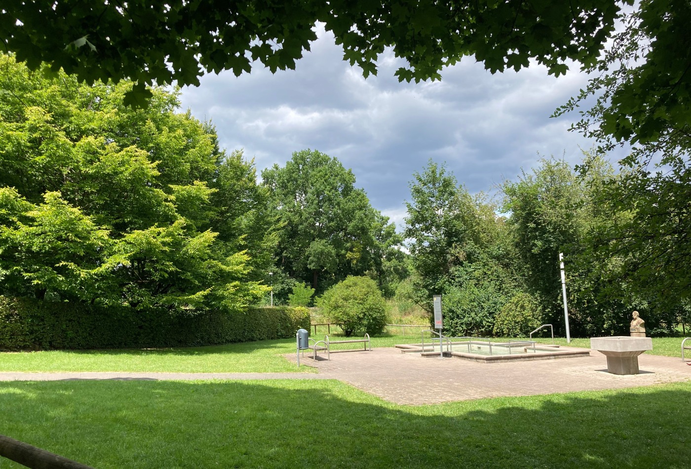 Kneippbecken auf einer grünen Wiese, umgeben von schattigen Bäumen