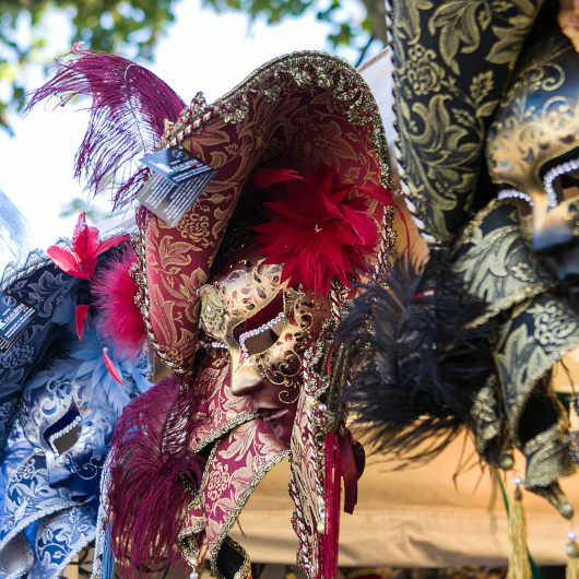 Zu sehen sind venezianische Masken in schwarz, rot und blau.