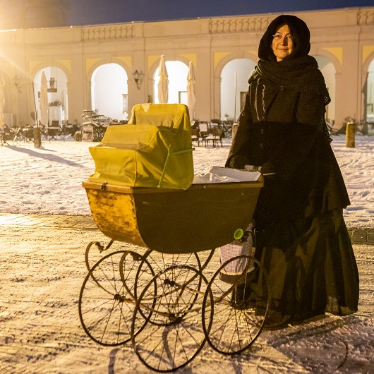 Die Gouvernante Caterina steht mit einem barocken Kinderwagen im Vorderen Schlosshof