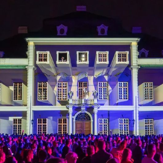 Eine Menschenmenge feiert vor der beleuchteten Fassade des Residenzschlosses