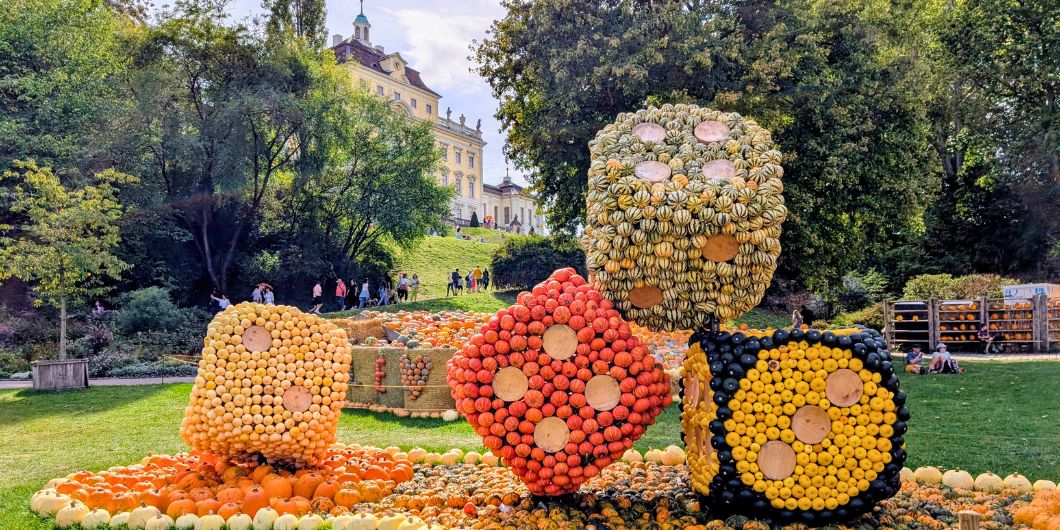 Vier große, mit Kürbissen besetzte Würfel liegen auf der Wiese vor dem Residenzschloss Ludwigsburg