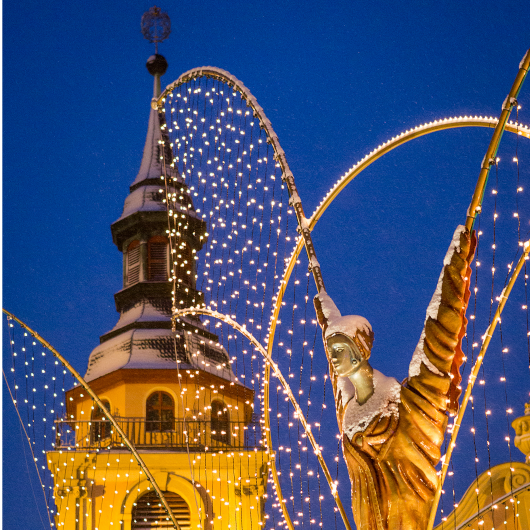 Zu sehen ist im Vordergrund ein Engel sowie im Hintergrund ein Teil der evangelischen Stadtkirche.