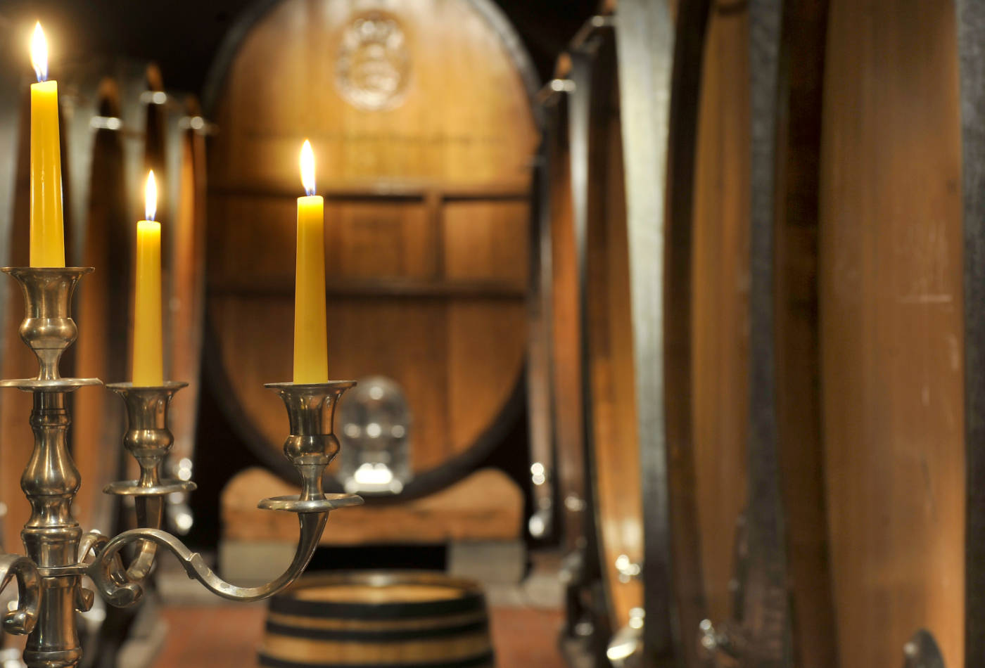 Blick auf illuminierten Kerzenleuchter und aufgereihte Weinfässer