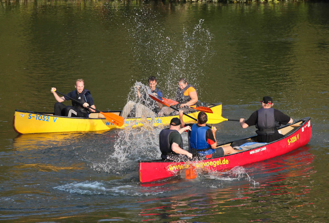 Zwei Kanus mit mehreren Personen auf einem Fluss. 