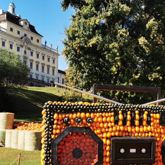 Im Vordergrund ist ein Radio geformt aus Kürbissen zu sehen, im Hintergrund ist das Residenzschloss Ludwigsburg zu erkennen.