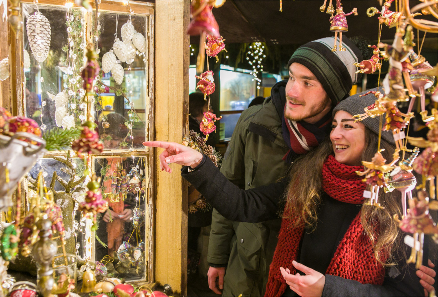 Paar steht vor Christbaumschmuck Hütte 