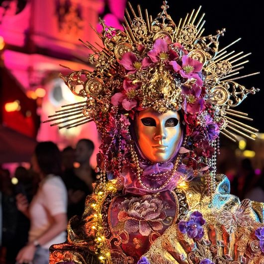 Ein Venezianischer Maskenträger bei Nacht vor der beleuchteten Stadtkirche Ludwigsburg