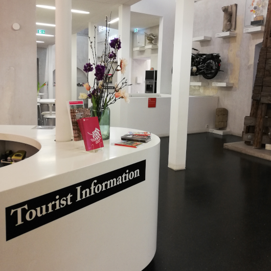Innenaufnahme der Tourist Information Ludwigsburg mit zwei Mitarbeiterinnen vor dem Tresen.
