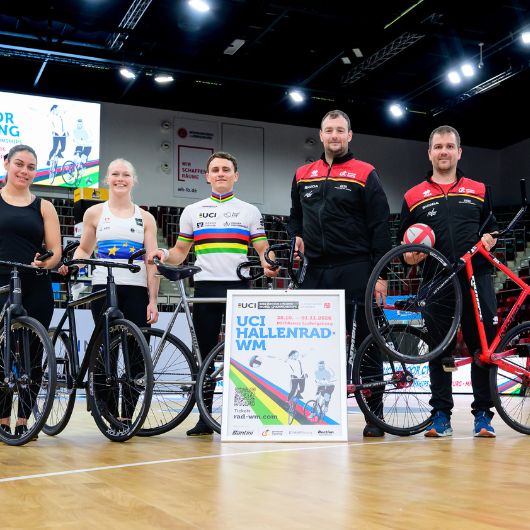 5 Hallenrad Athletinnen und Athleten stehen in der MHPArena mit einem Plakat zur WM 