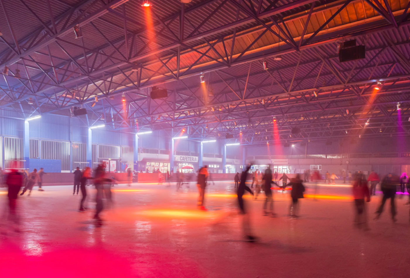 Kunsteisbahn mit orange-rotem Licht bei der Disco.