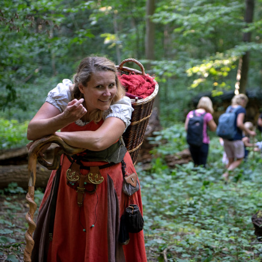 Hinter einem Baum schaut die Märchenhexe Steffi hervor.