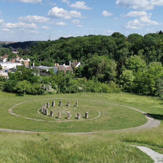 Steinkreis in der Mitte eines als Spirale gestalteten Wegs auf einer grünen Wiese.