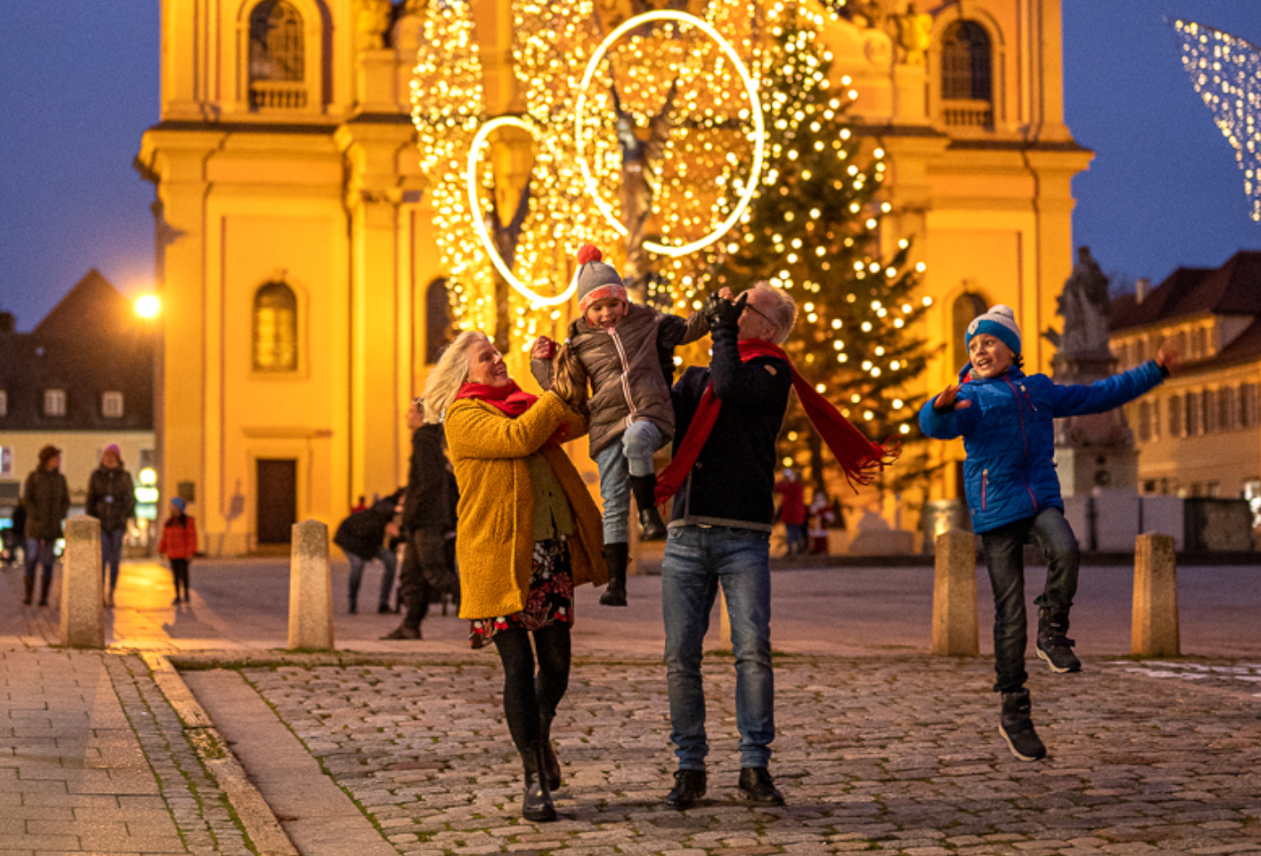 Familienglück in der Adventszeit Glückliche Familie auf dem golden erleuchteten Marktplatz