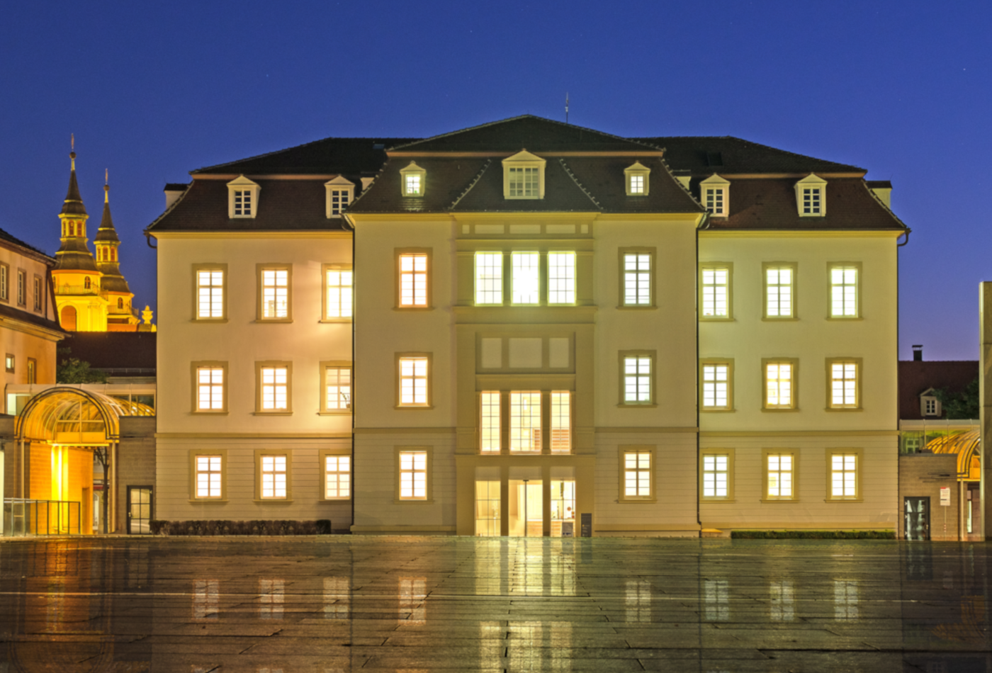 Das Rathaus bei Nacht. Sterne glänzen über dem Rathaus, die Fenster sind beleuchtet.