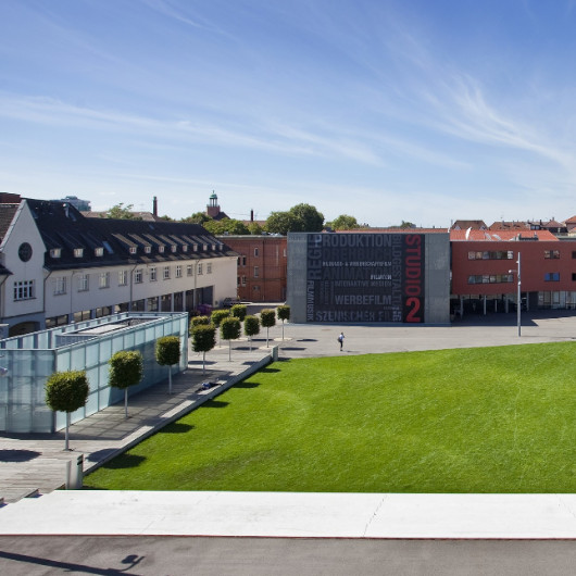 Blick auf den grünen Akademiehof, im Hintergrund die Filmakademie.