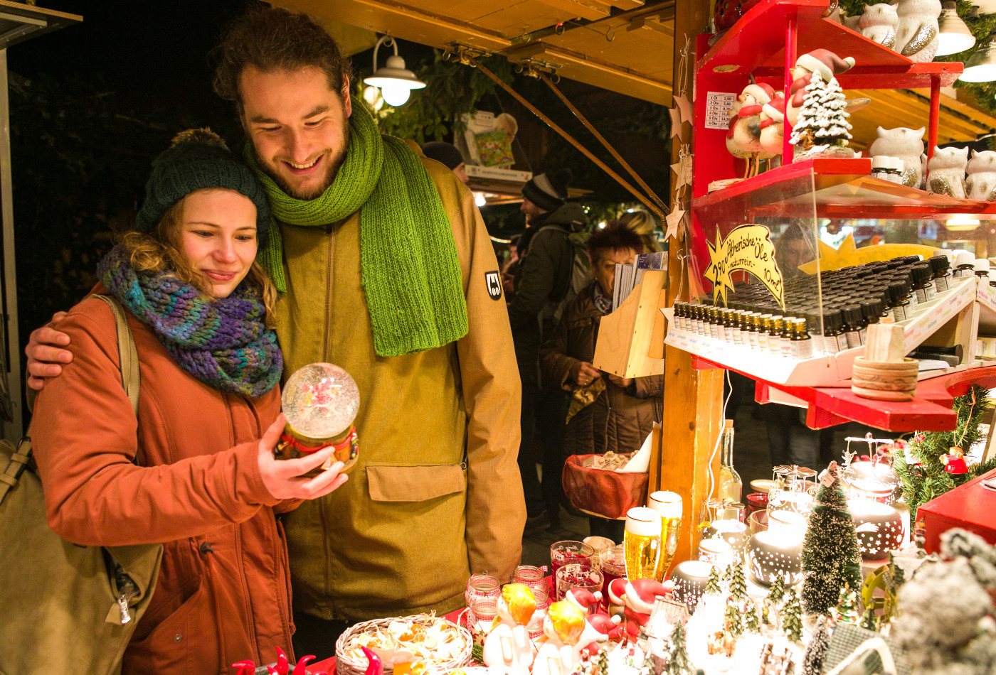 Pärchen bewundert Schneekugel an Weihnachtsmarkt Hütte