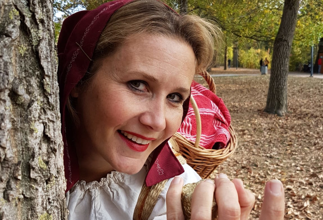 Märchenhexe Steffi schaut hinter einem Baum hervor.