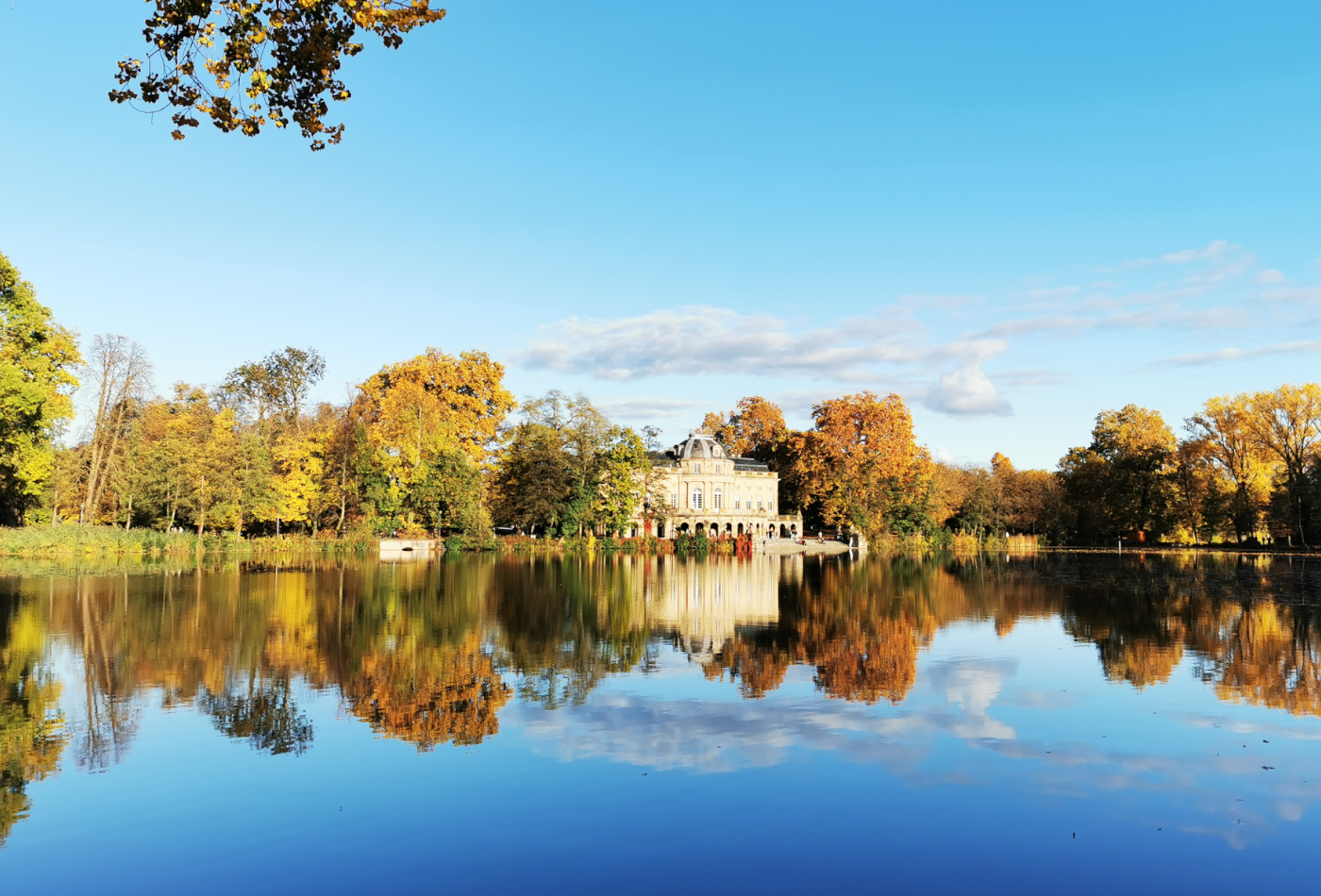 Seeschloss Monrepos im Herbst mit blauem Wasser im Vordergrund