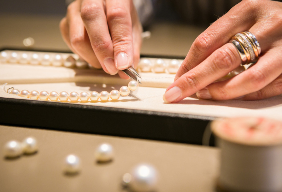 Pillen, Perlen und Pralinen Hände, die eine Perlenkette anfertigen.