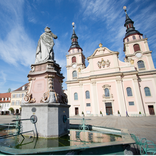 Zu sehen ist der Brunnen auf dem Marktplatz sowie im Hintergrund die evangelische Stadtkirche.