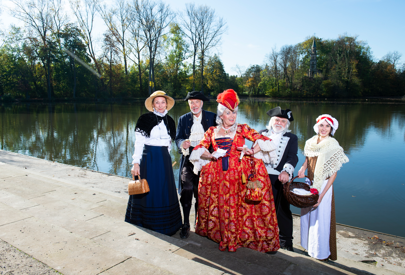 Fünf kostümierte Personen stehen vor einem See.