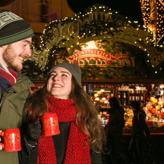 Zu sehen ist ein Pärchen, welches Glühwein trinkt.