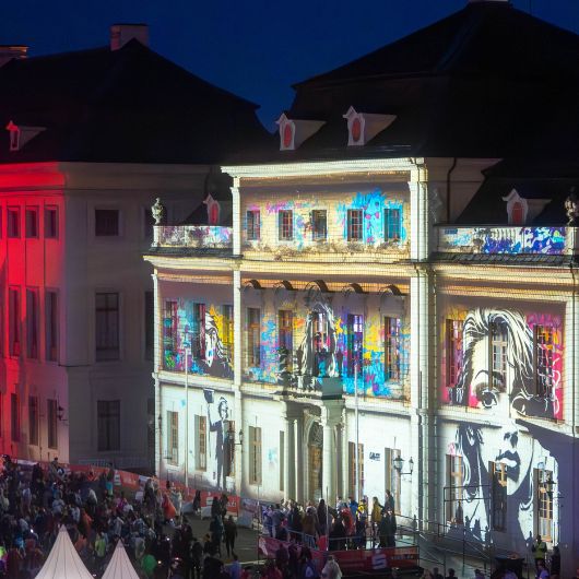 Eine Menschenmenge feiert vor der beleuchteten Fassade des Residenzschlosses