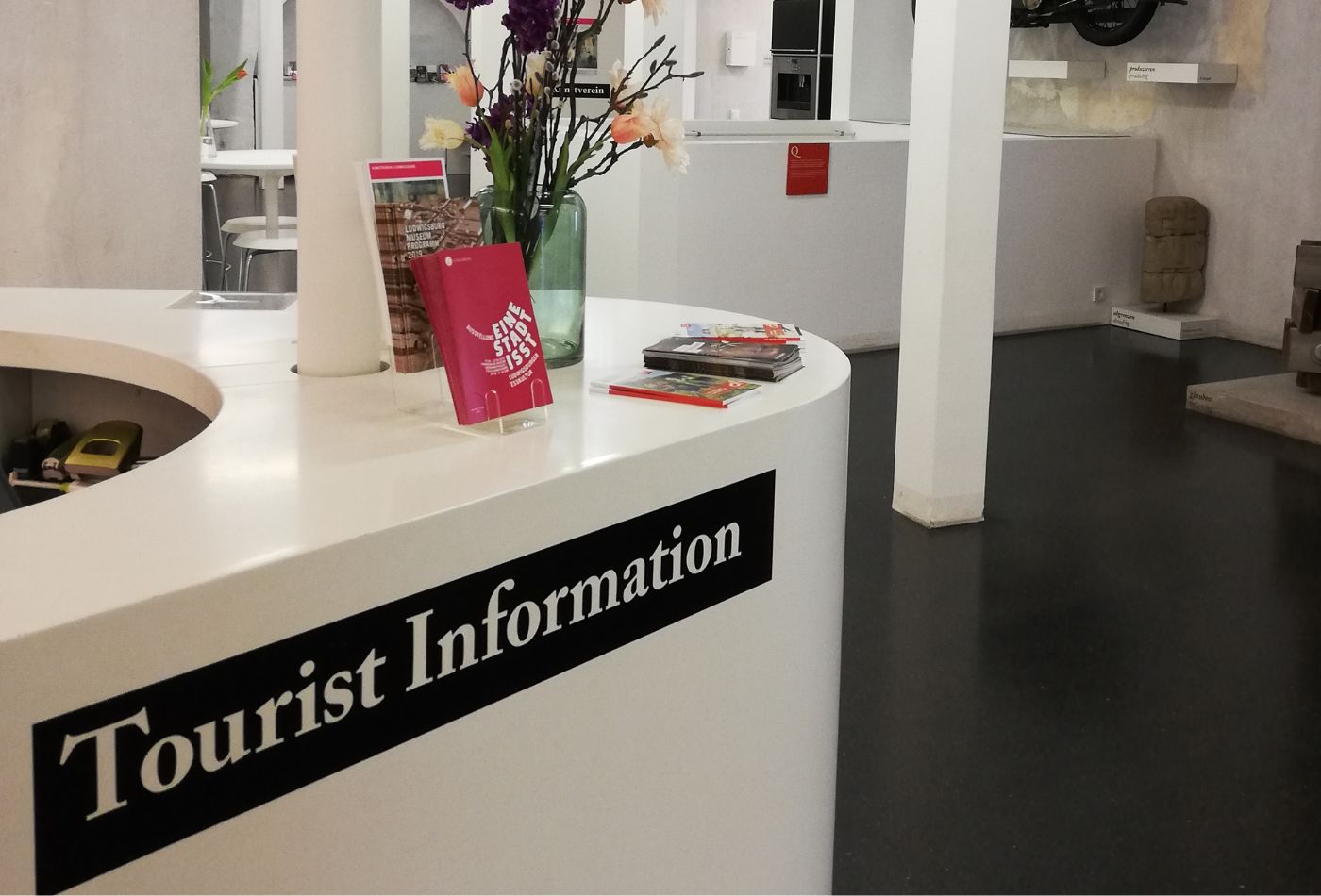 Frau im Rollstuhl lässt sich von einer Mitarbeiterin in der Tourist Info beraten.