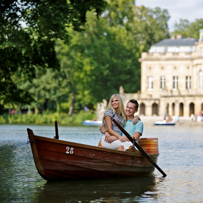 Ein Mann und eine Frau sind in einem Boot auf einem See, im Hintergrund ist das Schloss Monrepos
