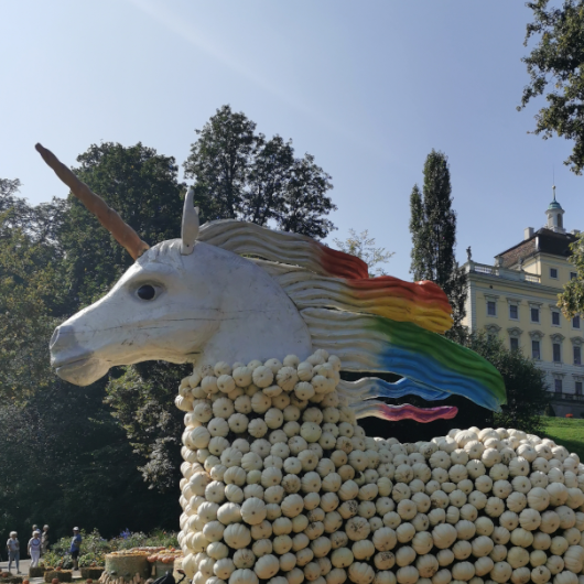 Im Vordergrund ist ein Einhorn geformt aus Kürbissen zu sehen, im Hintergrund ist das Residenzschloss Ludwigsburg zu erkennen.