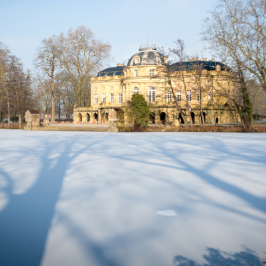 Zu sehen ist das verschneite Seeschloss Monrepos sowie der zugefrorene davorliegende See.